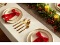 Festliche Weihnachtstischdeko mit weißen Tellern, roten Schleifen, goldenem Besteck und Girlande