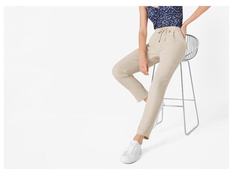 Beige Hose mit weißen Sneakers und einem Blusentop mit Blumenmuster.