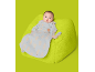 Baby in einem hellblauen Schlafsack mit Bärenmuster, liegend auf einem grünen Sitzsack.