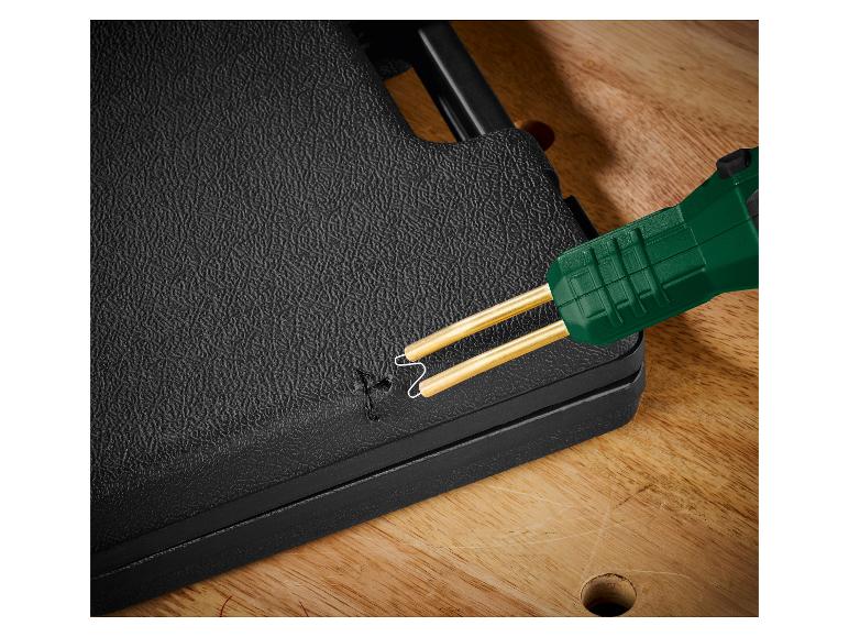 Kunststoffschweißgerät mit grünem Griff repariert eine schwarze Oberfläche.