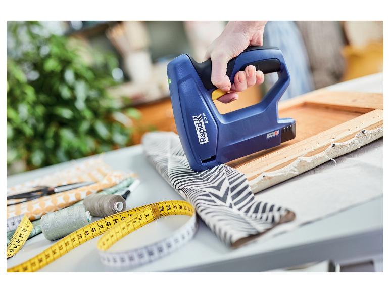 Blauer kabelloser Elektrotacker Rapid BTX10 in der Hand, der Stoff an einem Holzrahmen befestigt.