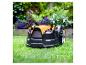 Orange-schwarzer Mähroboter auf grünem Rasen mit Blumen im Hintergrund.