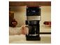 Kaffeemaschine mit Digitalanzeige und Kanne, von einer Person bedient.