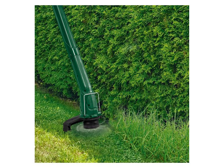 Rasentrimmer in Aktion, schneidet hohes Gras neben einer Hecke.