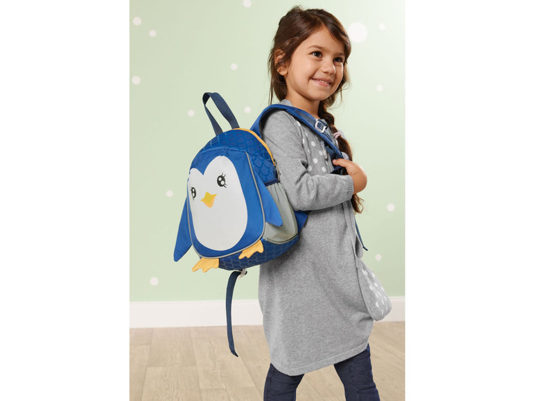 Ein Mädchen trägt einen blauen Rucksack mit einem Pinguin darauf.