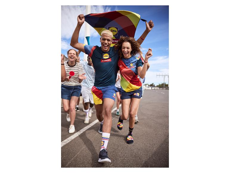 Eine Gruppe Menschen rennt und jubelt, trägt bunte gemusterte Sportbekleidung.