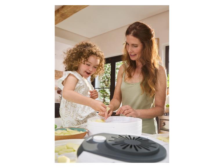 Mutter und Tochter trocknen Obst in einem Dörrautomat.