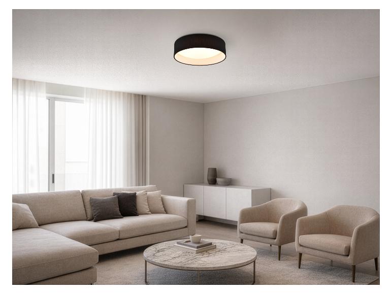Modernes Wohnzimmer mit modularem Sofa, rundem Couchtisch und Sesseln, beleuchtet von einer schwarzen Deckenleuchte.