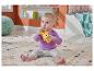 Baby sitzt auf einem Teppich und hält eine gelbe Affenrassel.