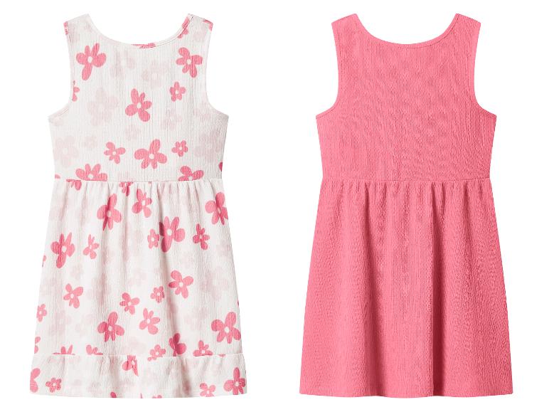 Zwei Kinder-Sommerkleider: eines weiß mit rosa Blumen und eines einfarbig rosa.