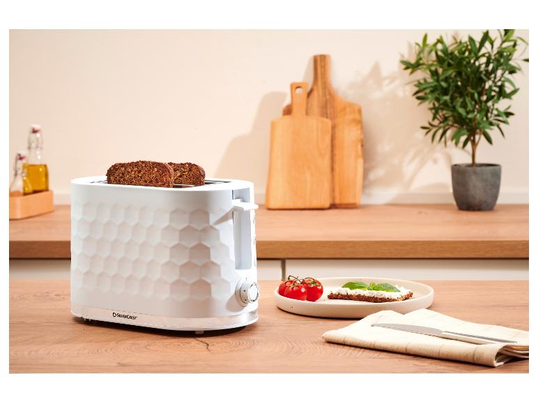 Weißer Toaster mit Wabenstruktur, mit Brotscheiben, auf einer Küchenarbeitsplatte.