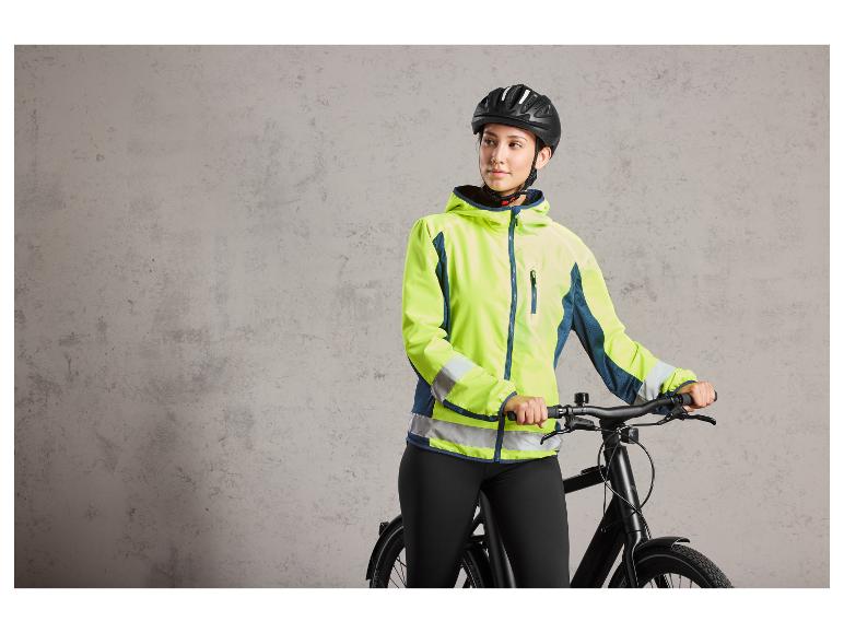 Eine Frau mit Fahrradhelm trägt eine fluoreszierende Jacke und hält ein Fahrrad fest.