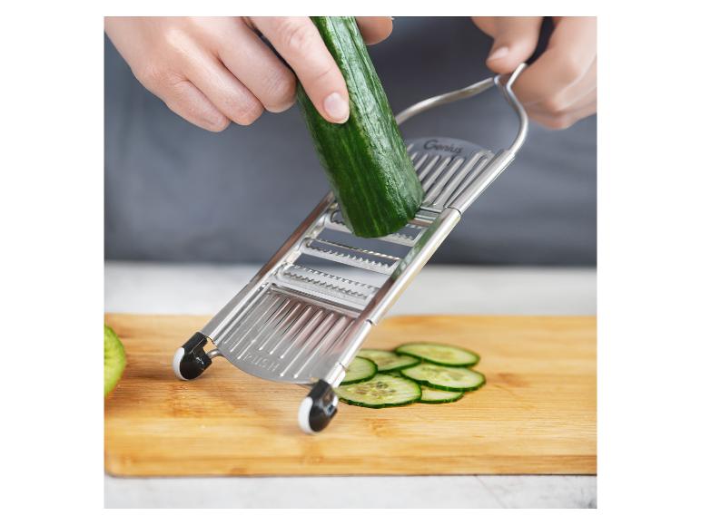 Hände schneiden Gurke mit einer Genius Mandoline auf einem Holzschneidebrett