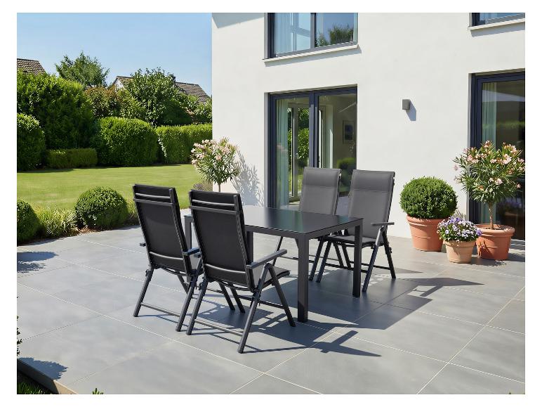 Gartenmöbel-Set mit schwarzem Tisch und Stühlen auf einer Terrasse, umgeben von Grün.