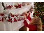 Mädchen arrangiert einen Adventskalender auf dem Kaminsims, mit Weihnachtsdekorationen.