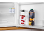 Offener Kühlschrank mit einer Kanne Wasser mit Himbeeren und einem Pfirsichsaftkarton.