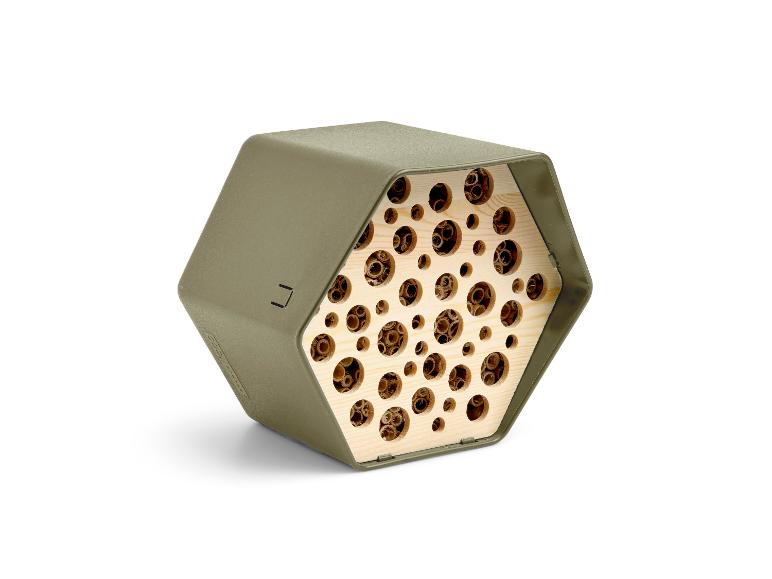 Sechseckiges Insektenhotel in Khaki mit Holzinterieur und Löchern.