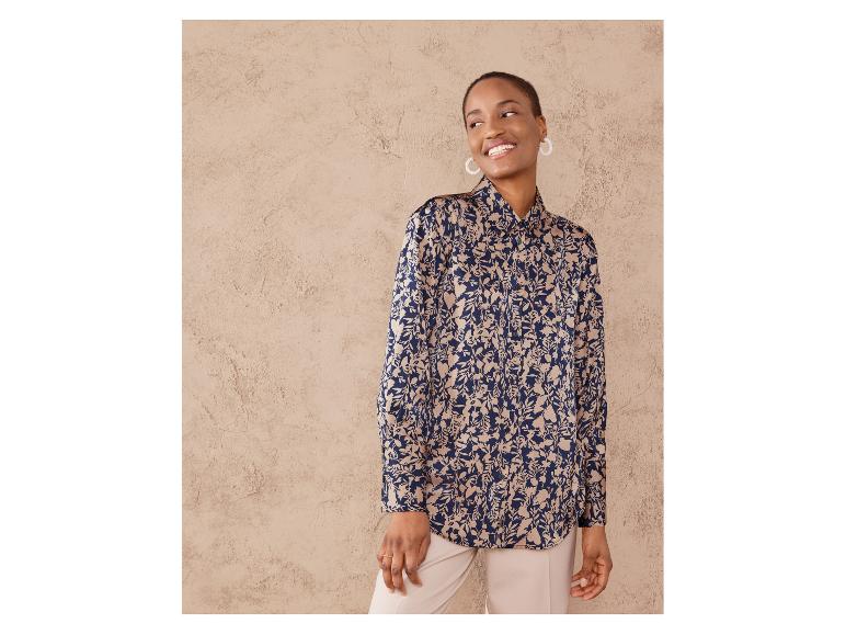 Eine Frau trägt eine blaue Bluse mit Blumendruck.