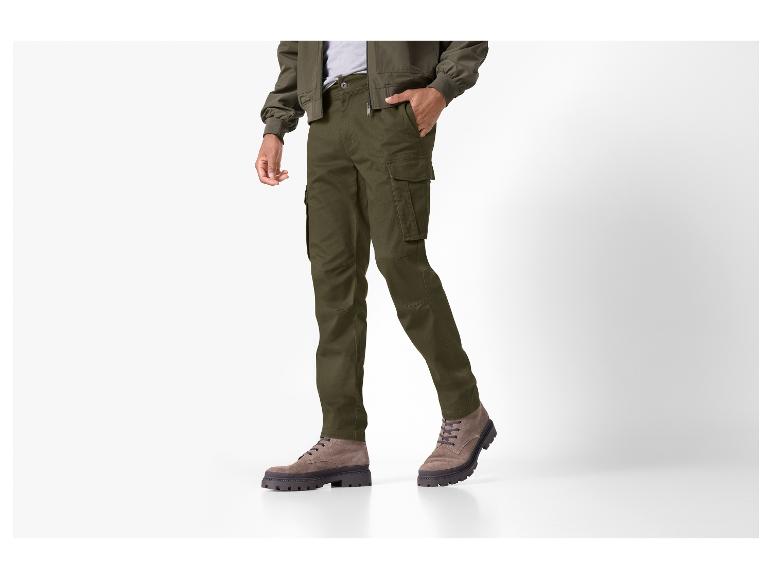 Mann in olivgrüner Cargohose, Bomberjacke und braunen Wildlederstiefeln.