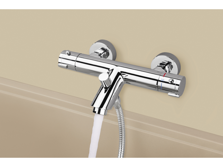 Verchromter Thermostat-Badewannenmischer mit Wasser, das in eine Wanne fließt.