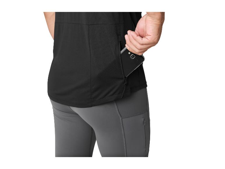 Mann in schwarzem T-Shirt und grauer Hose, der ein Telefon in eine Reißverschluss-Seitentasche steckt.