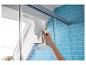 Handfenstersauger reinigt eine Duschwand in einem Badezimmer mit blauen Fliesen.