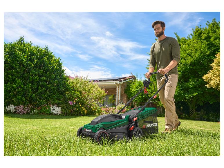 Ein Mann mäht mit einem Parkside Rasenmäher seinen Rasen.