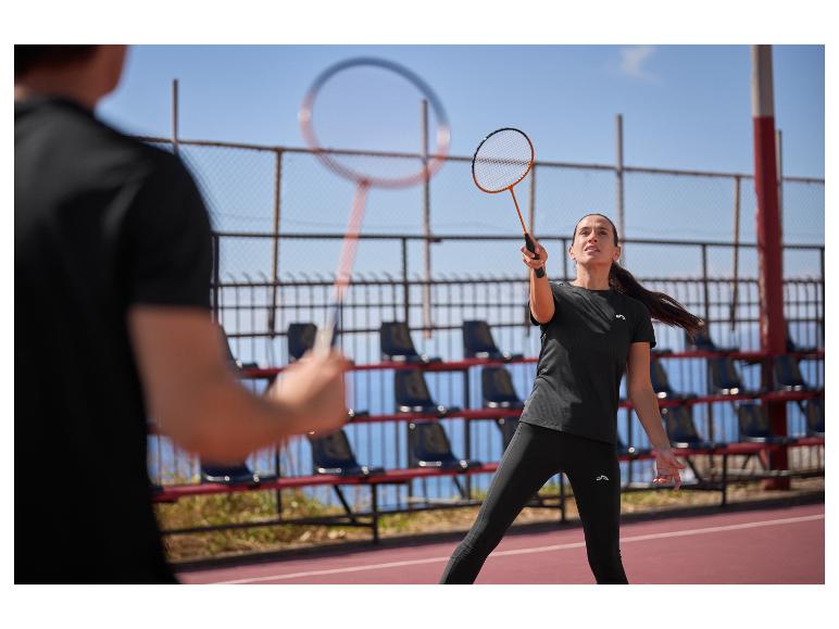 Frau und Mann spielen Badminton auf einem Außenplatz, gekleidet in schwarzer Sportkleidung.