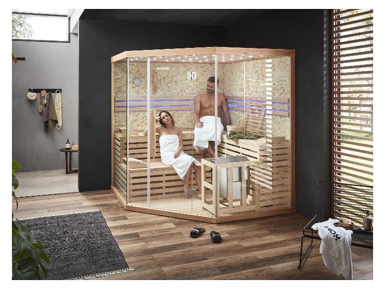 Zwei Personen entspannen in einer modernen HOME DELUXE Sauna mit Glaswänden und Holzbänken.