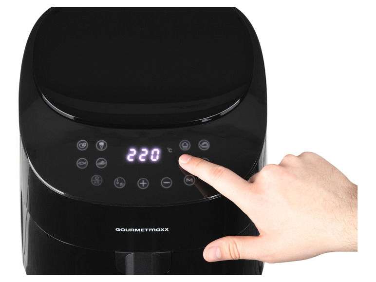 Eine schwarze Gourmetmaxx Fritteuse mit Touchscreen und einer Hand, die den Knopf 'manual' drückt.