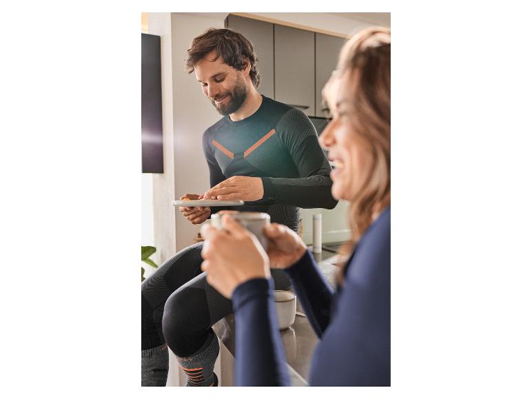 Mann und Frau in Sportkleidung, Mann hält ein Tablet, Frau trinkt aus einer Tasse.