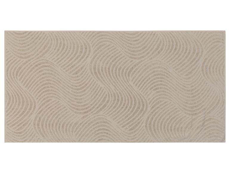 Beige Badematte mit Wellenmuster.