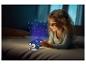 Lächelndes Mädchen im Bett mit einem Nachtlichtprojektor, der Sterne und einen Mond projiziert.