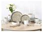 Elegantes Essgeschirr-Set mit gesprenkelten Tellern, Schalen, Tassen und Besteck auf hellem Holztisch.