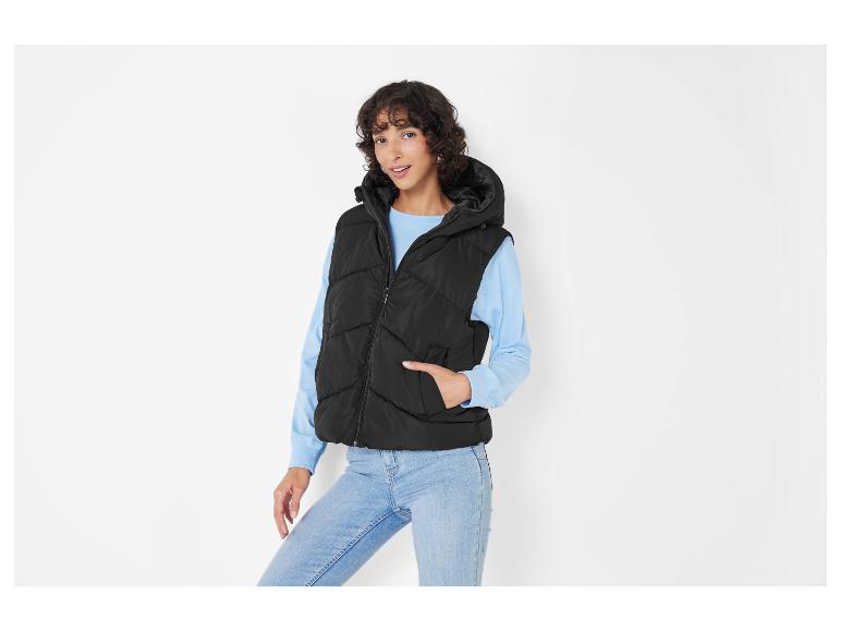 Eine Frau trägt eine schwarze Steppweste mit Kapuze.