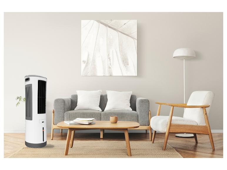 Weißer und grauer Turmventilator in einem Wohnzimmer mit grauem Sofa und Holzmöbeln.