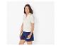 Frau in einem gerippten weißen Poloshirt mit Streifen und dunkelblauen Shorts.