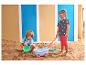Zwei Kinder spielen im Sandkasten mit Strandspielzeug, darunter ein Wagen und Eimer.