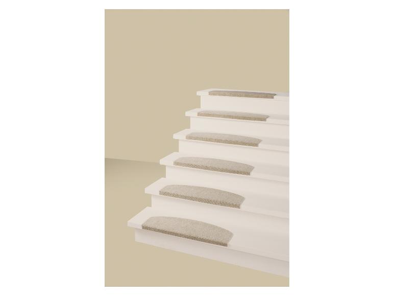 Weiße Treppe mit beigen Teppichstufen vor einer beigen Wand.