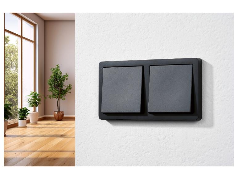 Zwei schwarze Lichtschalter an einer weißen Wand.