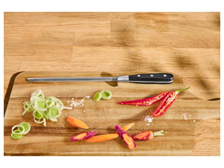 Wetzstahl mit geschnittenem Lauch, Karotten und Chilis auf einem Holzbrett.