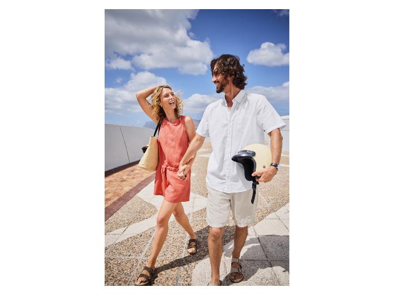 Paar in Sommerkleidung spaziert, Motorradhelm in der Hand.