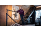 Ein Mädchen in einem weinroten Kapuzenpullover mit der Aufschrift 'PARIS' und dunklen Jeans steht auf einer Holztreppe.