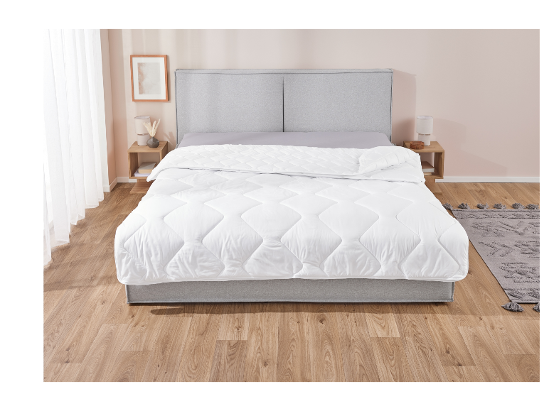 Weiße Daunendecke auf einem modernen grauen Bett.