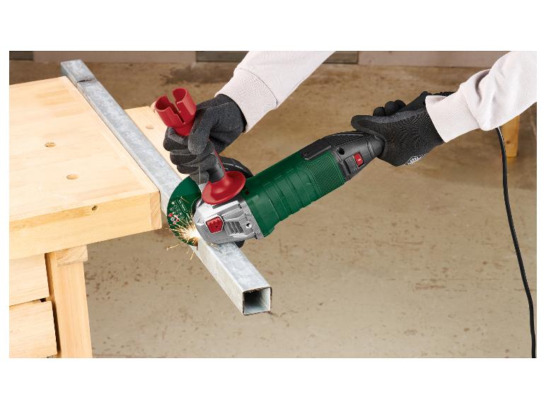 Person schneidet Metall mit einem Winkelschleifer, Funken fliegen, auf einer Holzwerkbank.