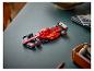 Ein roter Lego Ferrari Formel-1-Wagen auf einem dunkelgrünen Schreibtisch mit Büromaterial.