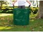 Person im Garten mit einem grünen Gartenabfallsack voller Blätter.