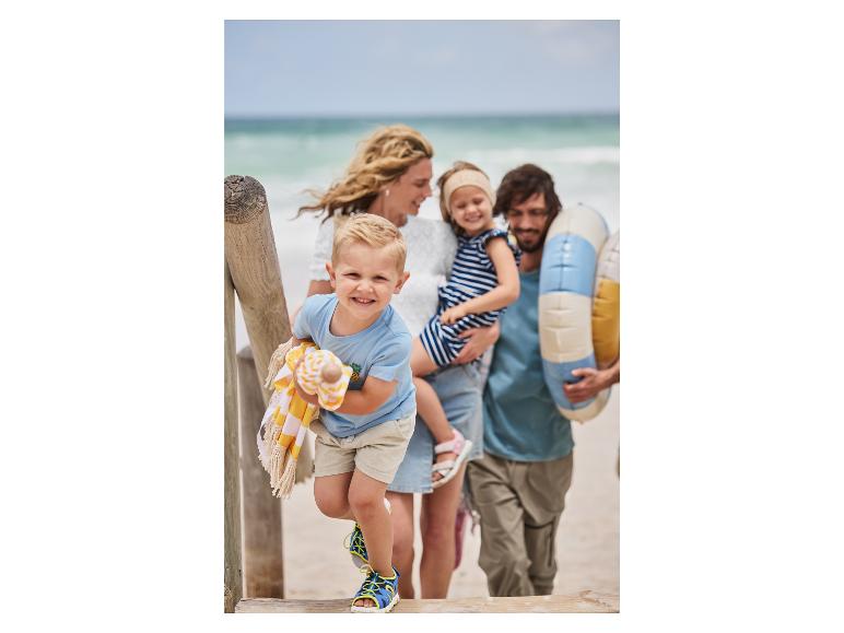 Kinder am Strand mit Handtuch und Luftreifen.