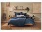 Schlafzimmer mit Holzbett, blauer Bettwäsche und natürlichen Dekoelementen.
