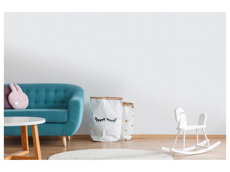 Kinderzimmer mit türkisfarbenem Sofa, weißen Aufbewahrungstaschen und weißem Schaukelpferd.